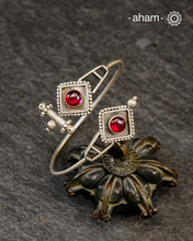 Adjustable 92.5 sterling silver handcuff with maroon stone highlight.