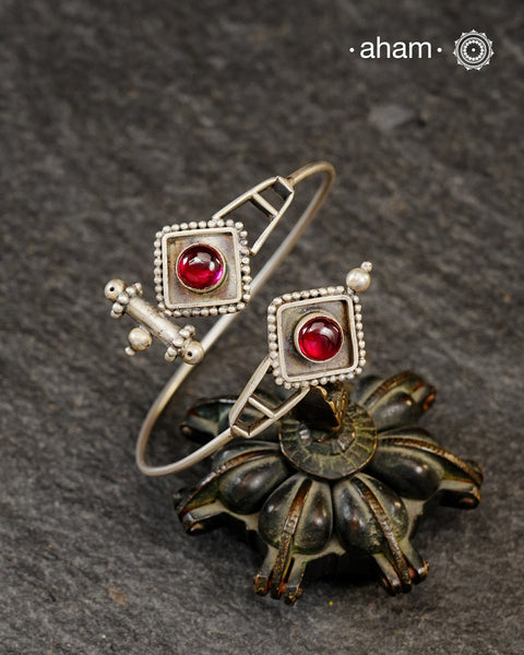 Adjustable 92.5 sterling silver handcuff with maroon stone highlight.