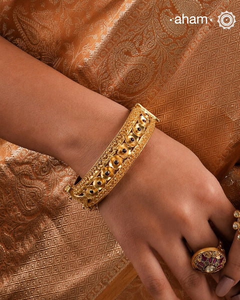 Expertly crafted in silver with a dazzling gold polish, this Intricate Gold Polish Silver Hand Kada is a true classic. Adorned with stunning tar work and kemp stone highlights, this timeless piece never goes out of style. Openable design adds convenience and versatility.The price is for one piece kada only.