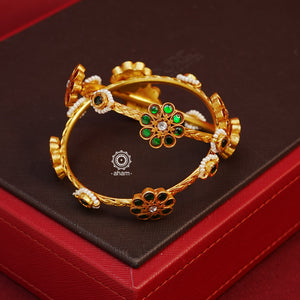 Introducing our Gold Polish Silver Bangles, crafted in silver with flawless gold polish. These beautiful bangles feature red and green alternating flowers with pearl highlights, making them the perfect complement to your classic Indian outfits. Experience the elegance and versatility of these bangles today.  Comes in a pair (2 bangles)