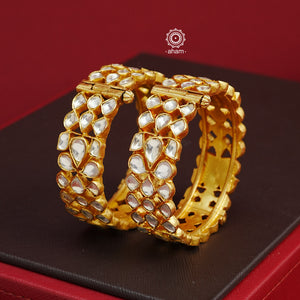 Add an elegant touch to your ethnic ensemble with our Kundan Gold Polish Silver Kada. Crafted in silver with a classic gold polish, these versatile Kadas are a must-have for weddings and special occasions. With the option to wear them alone or stacked, these Kadas are a versatile and timeless accessory. The price is for a set of 2 pieces kada only. 