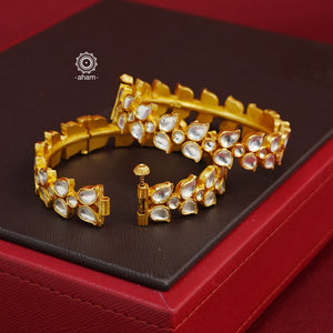 Add an elegant touch to your ethnic ensemble with our Kundan Gold Polish Silver Kada. Crafted in silver with a classic gold polish, these versatile Kadas are a must-have for weddings and special occasions. With the option to wear them alone or stacked, these Kadas are a versatile and timeless accessory.  The price is for a set of 2 pieces kada only. 