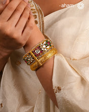 This openable Kundan Gold Polish Silver Kada gives the illusion of wearing two stacked kadas, with exquisite kundan work and laced pearls adding to its charm. Made with silver and finished in gold polish, it's a must-have for any jewellery collection.
