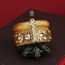 This openable Kundan Gold Polish Silver Kada gives the illusion of wearing two stacked kadas, with exquisite kundan work and laced pearls adding to its charm. Made with silver and finished in gold polish, it's a must-have for any jewellery collection.  The price is for one piece kada only.