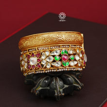 This openable Kundan Gold Polish Silver Kada gives the illusion of wearing two stacked kadas, with exquisite kundan work and laced pearls adding to its charm. Made with silver and finished in gold polish, it's a must-have for any jewellery collection.  The price is for one piece kada only.