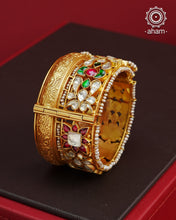 This openable Kundan Gold Polish Silver Kada gives the illusion of wearing two stacked kadas, with exquisite kundan work and laced pearls adding to its charm. Made with silver and finished in gold polish, it's a must-have for any jewellery collection.