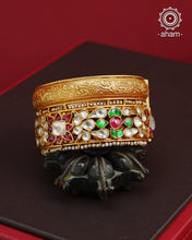 This openable Kundan Gold Polish Silver Kada gives the illusion of wearing two stacked kadas, with exquisite kundan work and laced pearls adding to its charm. Made with silver and finished in gold polish, it's a must-have for any jewellery collection.