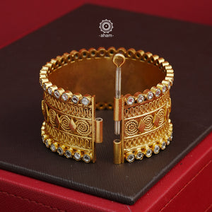 Crafted in 92.5 silver with gold polish, this statement kada features stunning zircon stone highlights. Elegant and eye-catching, this openable kada adds a touch of glamour to any outfit. The price is for a One pieces kada only. 