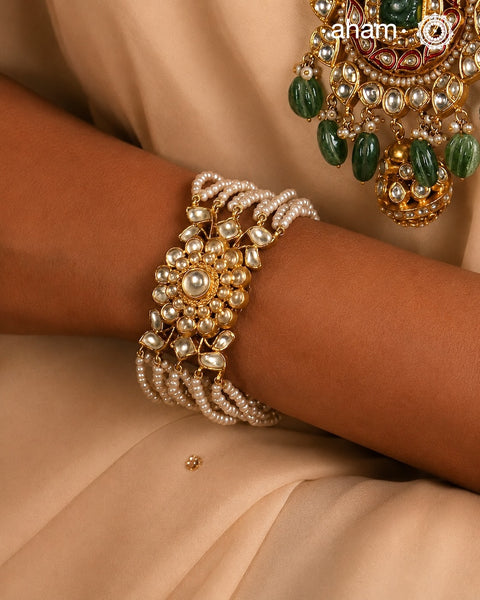Expertly handcrafted with intricate Kundan work, this sterling silver Bracelet features a stunning gold polish and delicate pearl handwork. Perfect for any festive occasion, it adds a touch of elegance to any outfit. Elevate your style with this beautiful piece.