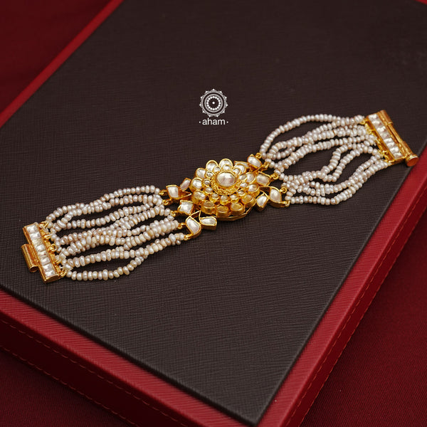 Expertly handcrafted with intricate Kundan work, this sterling silver Bracelet features a stunning gold polish and delicate pearl handwork. Perfect for any festive occasion, it adds a touch of elegance to any outfit. Elevate your style with this beautiful piece.