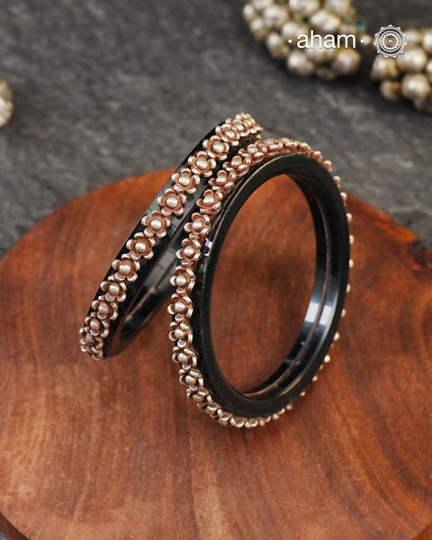 Beautiful tribal silver Bangles. Perfectly crafted silver flowers set on Black plastic bangles. Comes as a set of 2 Bangles