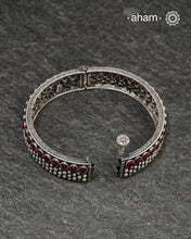 This handcrafted kada showcases the exceptional skill of Kolhapur's master karigars, created entirely from 92.5 sterling silver with striking kemp stone accents. The bangle demonstrates superior craftsmanship through its precise construction and refined finish. Kemp highlights add textural depth and visual interest to the classic kada silhouette. An investment piece that honours traditional jewellery-making heritage while offering versatile styling for both formal occasions and daily adornment.