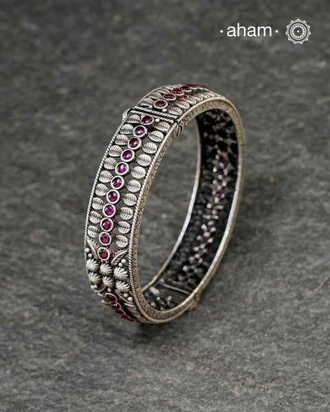 This handcrafted kada showcases the exceptional skill of Kolhapur's master karigars, created entirely from 92.5 sterling silver with striking kemp stone accents. The bangle demonstrates superior craftsmanship through its precise construction and refined finish. Kemp highlights add textural depth and visual interest to the classic kada silhouette. An investment piece that honours traditional jewellery-making heritage while offering versatile styling for both formal occasions and daily adornment.
