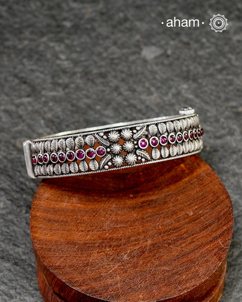 This handcrafted kada showcases the exceptional skill of Kolhapur's master karigars, created entirely from 92.5 sterling silver with striking kemp stone accents. The bangle demonstrates superior craftsmanship through its precise construction and refined finish. Kemp highlights add textural depth and visual interest to the classic kada silhouette. An investment piece that honours traditional jewellery-making heritage while offering versatile styling for both formal occasions and daily adornment.