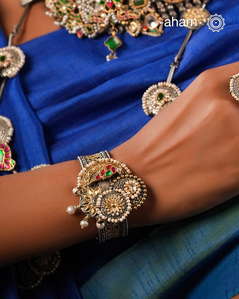 Noori two tone silver open hand cuff with a vibrant peacock motif. An eclectic mix of elements, with a play of colours, textures, forms and workmanship. Handcrafted in 92.5 Sterling Silver with two tones that make them so versatile and unique. Modern Heirloom pieces that can be worn across generations. 
