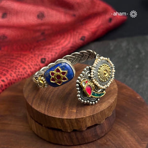 This Noori Two Tone Lapiz Stone Silver Cuff is a work of art. The braided cuff features a lapiz stone with kundan inlay on one side and a red green bird on the other, creating a classic dual tone design. Expertly crafted, this cuff is a stunning addition to any jewelry collection.
The price is for one piece kada only. 

