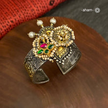 Noori two tone silver open hand cuff with a vibrant peacock motif. An eclectic mix of elements, with a play of colours, textures, forms and workmanship. Handcrafted in 92.5 Sterling Silver with two tones that make them so versatile and unique. Modern Heirloom pieces that can be worn across generations. 
The price is for one piece kada only. 

