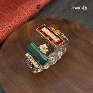 Introducing the Noori Two Tone Silver Cuff, a beautifully crafted open cuff in 92.5 silver featuring a two-tone braided band adorned with stunning green and pink kundan and parrot designs. Elevate your style with this unique and elegant piece, perfect for any occasion.

The price is for one piece kada only.