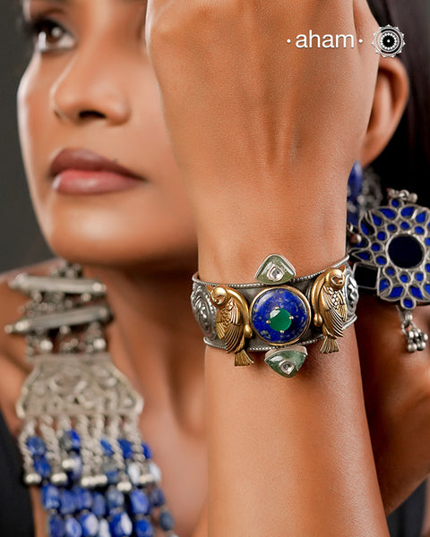 One of a kind statement wearable art pieces crafted in 92.5 silver.Silver hand kada with two tone gold polish kundan work.A beautiful Lapiz stone in the center with detailed birds on the size.