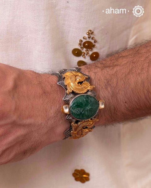 Noori two tone silver open hand cuff with a vibrant peacock motif and carved green onyx in the center. An eclectic mix of elements, with a play of colours, textures, forms and workmanship. Handcrafted in 92.5 Sterling Silver with two tones that make them so versatile and unique. Modern Heirloom pieces that can be worn across generations.

