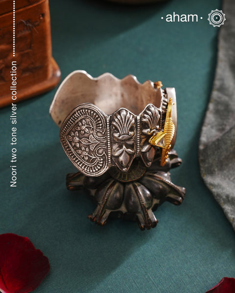 Noori two tone silver open hand cuff with a vibrant peacock motif and carved green onyx in the center. An eclectic mix of elements, with a play of colours, textures, forms and workmanship. Handcrafted in 92.5 Sterling Silver with two tones that make them so versatile and unique. Modern Heirloom pieces that can be worn across generations.
The price is for one piece kada only.