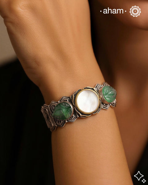 This unique Noori Two Tone Silver Hand Cuff (Open Cuff) is handcrafted using 92.5 silver, featuring a beautiful mother of pearl center and intricately carved green onyx on the sides. Truly a statement piece of wearable art.