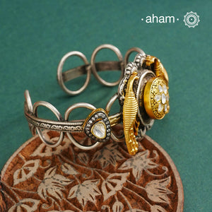 The Noori Two Tone Peacock Silver Cuff showcases expert craftsmanship in 92.5 sterling silver, featuring a distinctive blend of two-tone hues and a Victorian finish. Its intricate textures and elegant forms create a versatile accessory that complements both contemporary and classic styles, making it a unique statement piece for any collection.