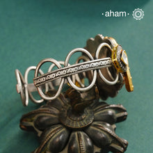 The Noori Two Tone Peacock Silver Cuff showcases expert craftsmanship in 92.5 sterling silver, featuring a distinctive blend of two-tone hues and a Victorian finish. Its intricate textures and elegant forms create a versatile accessory that complements both contemporary and classic styles, making it a unique statement piece for any collection.