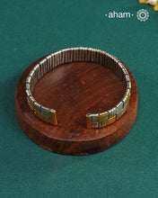 Elevate your wrist game with this striking two-tone hand cuff, masterfully crafted to bridge traditional and contemporary aesthetics. The intricate weave pattern showcases the artistry of handcrafted silver work, while the interplay of gold and silver tones adds sophisticated depth. Versatile enough to complement your ethnic ensembles or modern Western wardrobe, this statement piece transitions seamlessly from day to evening wear. A timeless investment for those who appreciate refined craftsmanship and unde