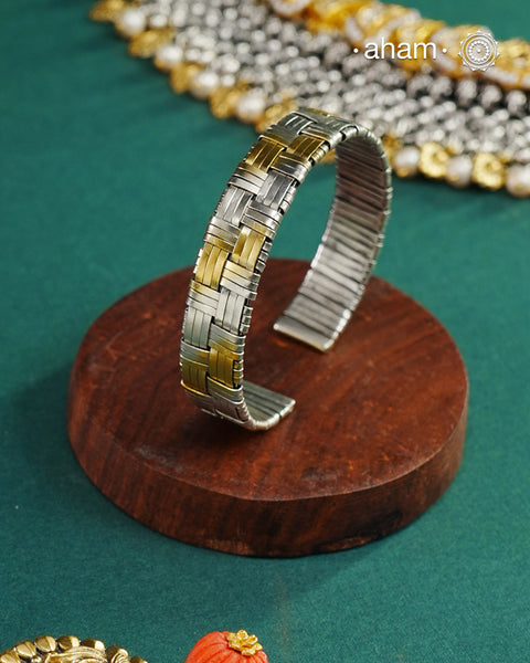 Elevate your wrist game with this striking two-tone hand cuff, masterfully crafted to bridge traditional and contemporary aesthetics. The intricate weave pattern showcases the artistry of handcrafted silver work, while the interplay of gold and silver tones adds sophisticated depth. Versatile enough to complement your ethnic ensembles or modern Western wardrobe, this statement piece transitions seamlessly from day to evening wear. A timeless investment for those who appreciate refined craftsmanship and unde
