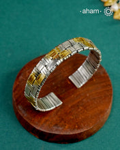 Elevate your wrist game with this striking two-tone hand cuff, masterfully crafted to bridge traditional and contemporary aesthetics. The intricate weave pattern showcases the artistry of handcrafted silver work, while the interplay of gold and silver tones adds sophisticated depth. Versatile enough to complement your ethnic ensembles or modern Western wardrobe, this statement piece transitions seamlessly from day to evening wear. A timeless investment for those who appreciate refined craftsmanship and unde