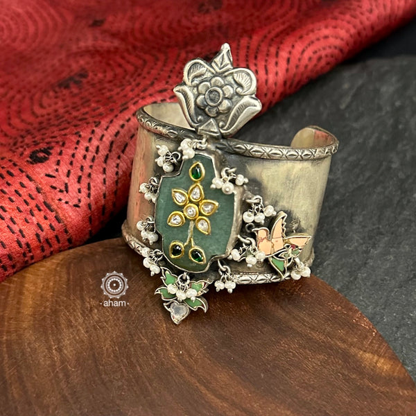 Introducing the Ira Silver HandCuff, a bold statement piece that exudes confidence. Made from 92.5 silver, it features stunning green onyx with intricate kundan inlay work and delicate pearls. Perfect for minimal accessorizing while still making a statement. Let your wrists do the talking with this chic and unique cuff.