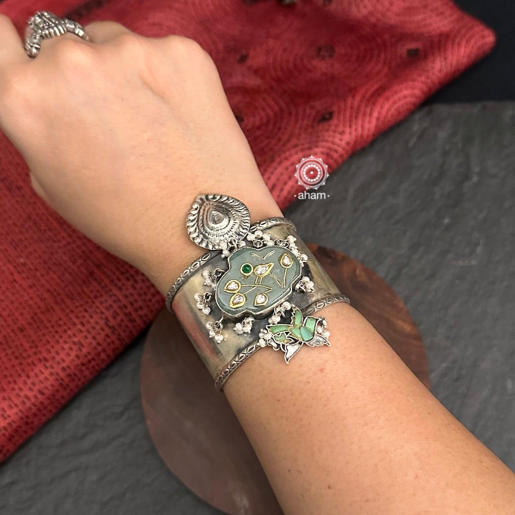 Introducing the Ira Silver HandCuff, a bold statement piece that exudes confidence. Made from 92.5 silver, it features stunning jade with intricate kundan inlay work and delicate pearls. Perfect for minimal accessorizing while still making a statement. Let your wrists do the talking with this chic and unique cuff.