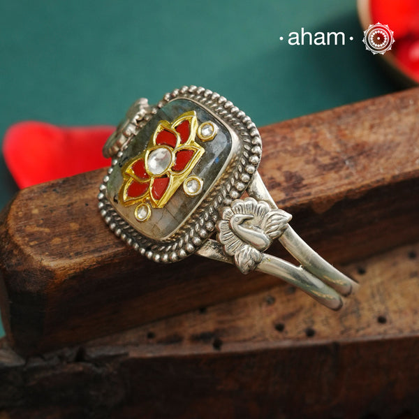 The Ira Lotus Silver Hand Cuff showcases a delicate lotus motif adorned with kundan stones, set on a captivating labradorite stone. Handmade in 92.5 silver, this elegant cuff complements any style—whether worn solo for a subtle statement or stacked alongside your watch and other bracelets for a layered, sophisticated look. Its expert craftsmanship ensures both beauty and lasting quality.