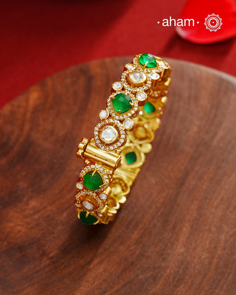 Moissanite kada that is expertly crafted from 92.5% sterling silver with fine gold polish finish, showcasing a refined and elegant appearance. They are beautifully set with brilliant moissanite stones and faux emeralds that closely mimic the sparkle of real stones, adding exceptional brilliance. The openable size 2.4 design offers a comfortable and adjustable fit, making this piece a sophisticated addition to any jewellery collection.