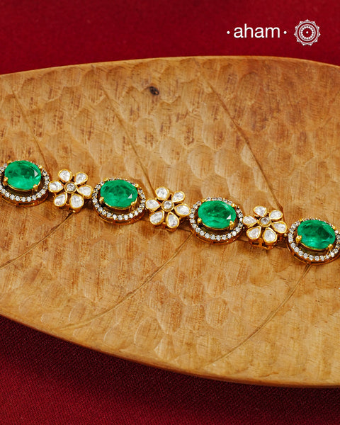 Handcrafted in 92.5 silver with a gold polish finish, this elegant bracelet features dazzling moissanite stones, floral motifs, and vibrant green accents. A timeless statement piece designed to elevate festive, wedding, and occasion wear.