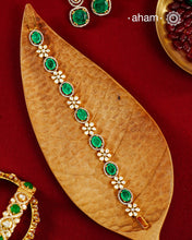 Handcrafted in 92.5 silver with a gold polish finish, this elegant bracelet features dazzling moissanite stones, floral motifs, and vibrant green accents. A timeless statement piece designed to elevate festive, wedding, and occasion wear.