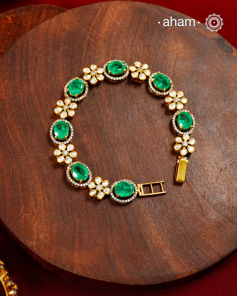 Handcrafted in 92.5 silver with a gold polish finish, this elegant bracelet features dazzling moissanite stones, floral motifs, and vibrant green accents. A timeless statement piece designed to elevate festive, wedding, and occasion wear.