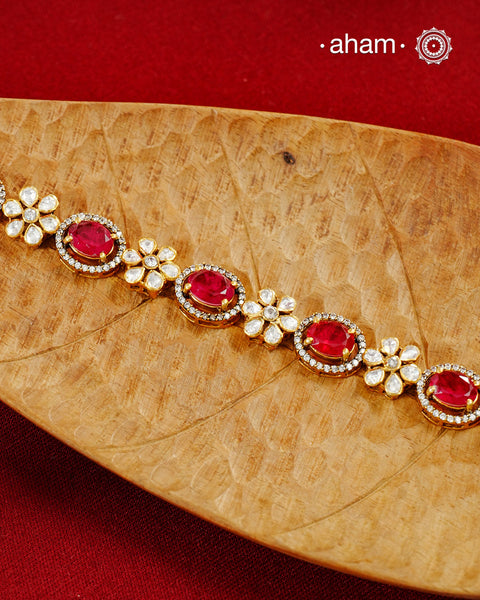 Handcrafted in 92.5 silver with a gold polish finish, this elegant bracelet features dazzling moissanite stones, floral motifs, and vibrant red accents. A timeless statement piece designed to elevate festive, wedding, and occasion wear.