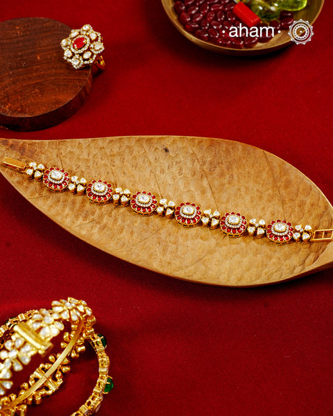 Handcrafted in 92.5 silver with a gold polish finish, this elegant bracelet features dazzling moissanite stones, floral motifs, and vibrant red accents. A timeless statement piece designed to elevate festive, wedding, and occasion wear.