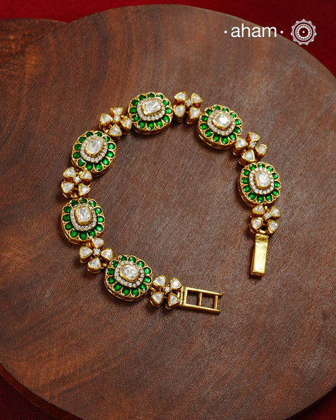 Handcrafted in 92.5 silver with a gold polish finish, this elegant bracelet features dazzling moissanite stones, floral motifs, and vibrant green accents. A timeless statement piece designed to elevate festive, wedding, and occasion wear.