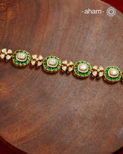 Handcrafted in 92.5 silver with a gold polish finish, this elegant bracelet features dazzling moissanite stones, floral motifs, and vibrant green accents. A timeless statement piece designed to elevate festive, wedding, and occasion wear.