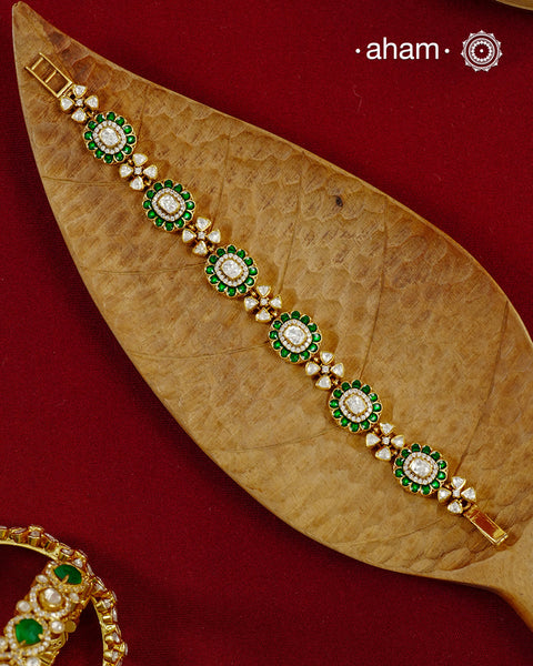 Handcrafted in 92.5 silver with a gold polish finish, this elegant bracelet features dazzling moissanite stones, floral motifs, and vibrant green accents. A timeless statement piece designed to elevate festive, wedding, and occasion wear.