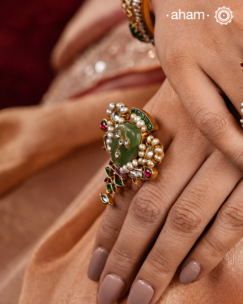 Crafted in 92.5 silver and dipped in gold polish, the Kundan Gold Polish Silver Ring features a beautiful festive design with stone inlay work, kundan setting, and delicate pearls. Perfect for adding an elegant touch to any festive occasion.