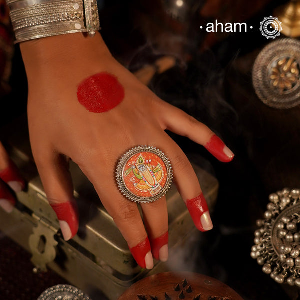 92.5 Sterling silver ring with an intricate hand painted Krishna motif in vibrant colours. 
 Enclosed with a glass top and an adjustable silver ring band, these are one of a kind wearable art pieces.