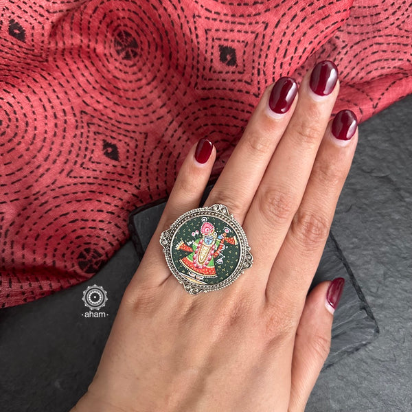 92.5 Sterling silver ring with an intricate hand painted Krishna motif in vibrant colours. Enclosed with a glass top and an adjustable ring band, these are one of a kind wearable art pieces. 