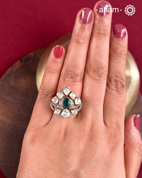 Crafted from 92.5% sterling silver with a rich gold polish, this ring showcases a captivating green emerald-like center stone. Surrounding it, moissanite stones add exceptional sparkle and brilliance, enhancing the ring’s luxurious appeal. Designed with precision, this piece offers a perfect blend of elegance and glamour for discerning jewellery enthusiasts.