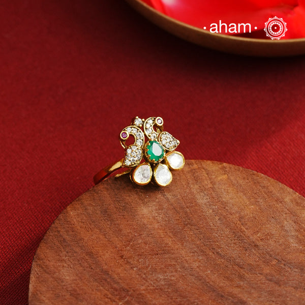 This exquisite ring features 92.5 sterling silver with a fine gold polish, showcasing a peacock motif that symbolizes elegance and grace. At its center lies a vibrant green emerald-like stone, surrounded by sparkling moissanite stones and delicate American diamonds, enhancing its brilliance. Expertly crafted, this piece combines traditional artistry with contemporary sparkle, making it a distinguished addition to any jewelry collection.