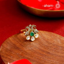 This exquisite ring features 92.5 sterling silver with a fine gold polish, showcasing a peacock motif that symbolizes elegance and grace. At its center lies a vibrant green emerald-like stone, surrounded by sparkling moissanite stones and delicate American diamonds, enhancing its brilliance. Expertly crafted, this piece combines traditional artistry with contemporary sparkle, making it a distinguished addition to any jewelry collection.
