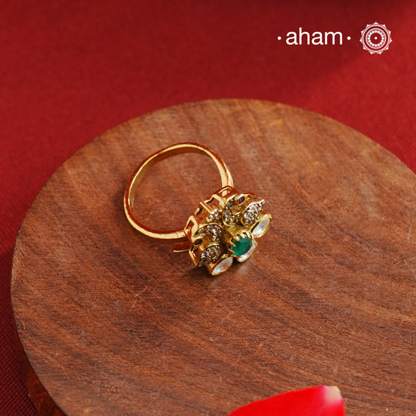 This exquisite ring features 92.5 sterling silver with a fine gold polish, showcasing a peacock motif that symbolizes elegance and grace. At its center lies a vibrant green emerald-like stone, surrounded by sparkling moissanite stones and delicate American diamonds, enhancing its brilliance. Expertly crafted, this piece combines traditional artistry with contemporary sparkle, making it a distinguished addition to any jewelry collection.